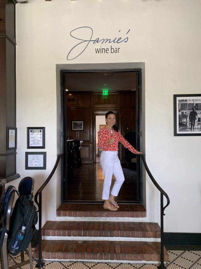 A woman posing at the entrance of a venue with 'James were be' sign above.
