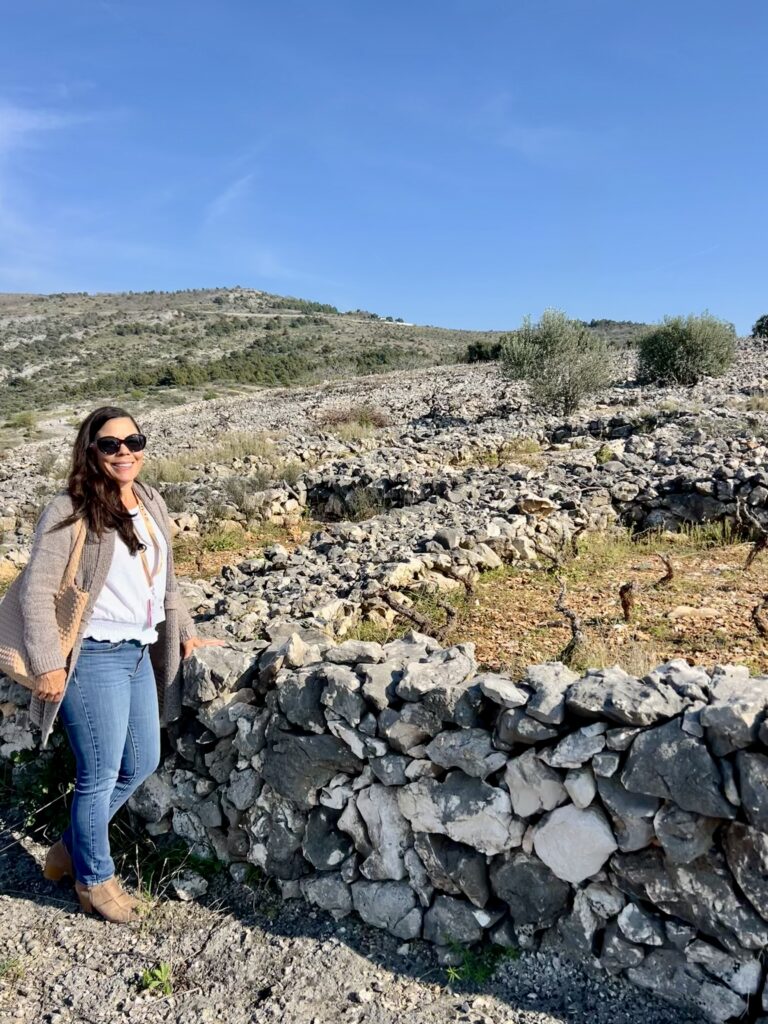 Woman standing near ancient stone walls under a clear blue sky.