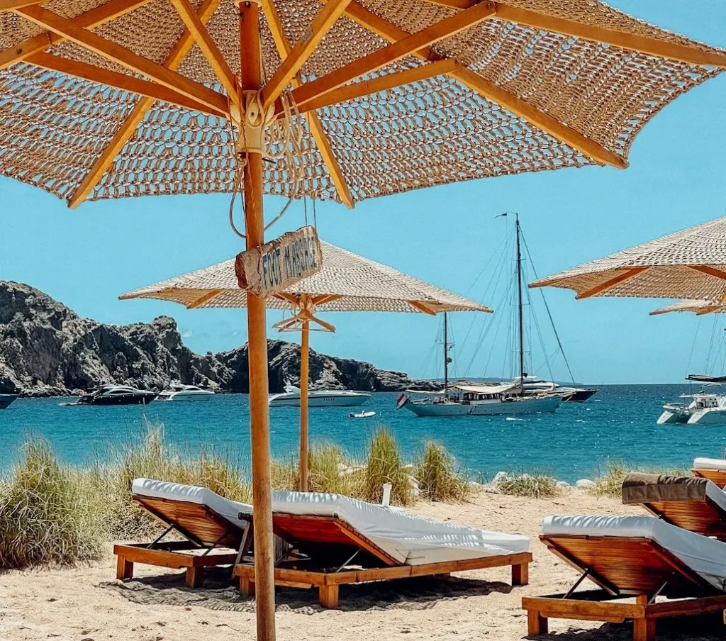 Beach chairs and umbrellas by the clear blue sea on a sunny day.