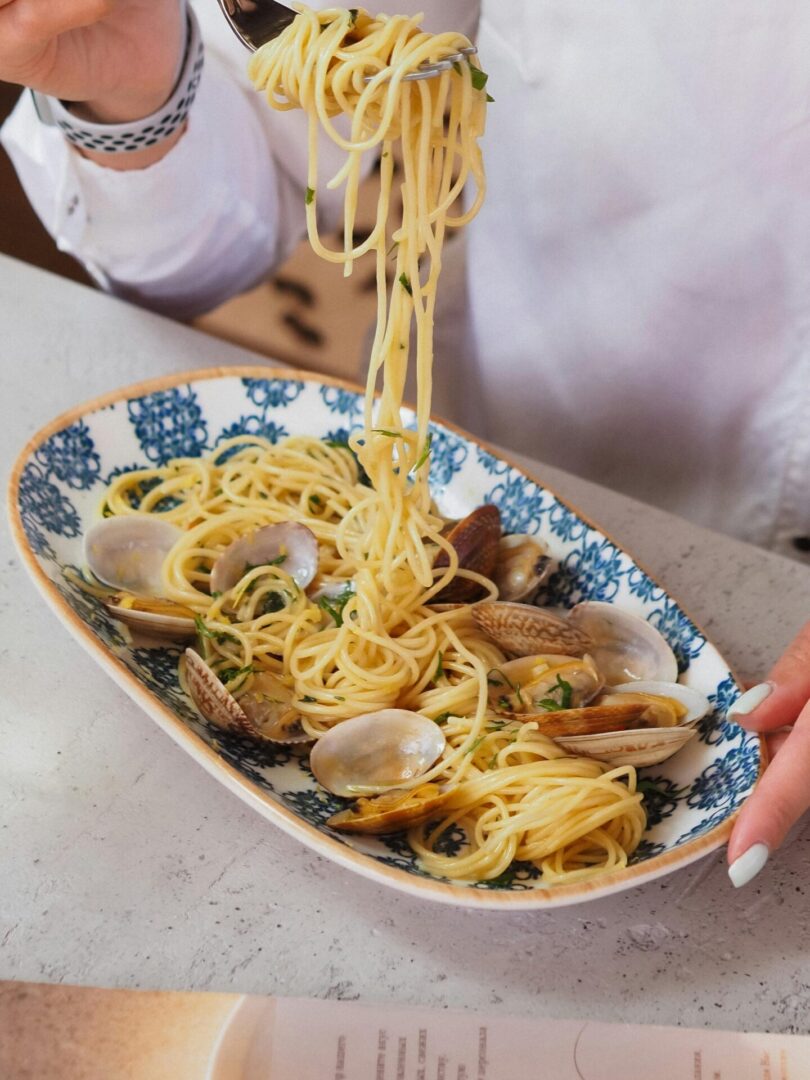 Capture of a gourmet seafood spaghetti meal paired with white wine.