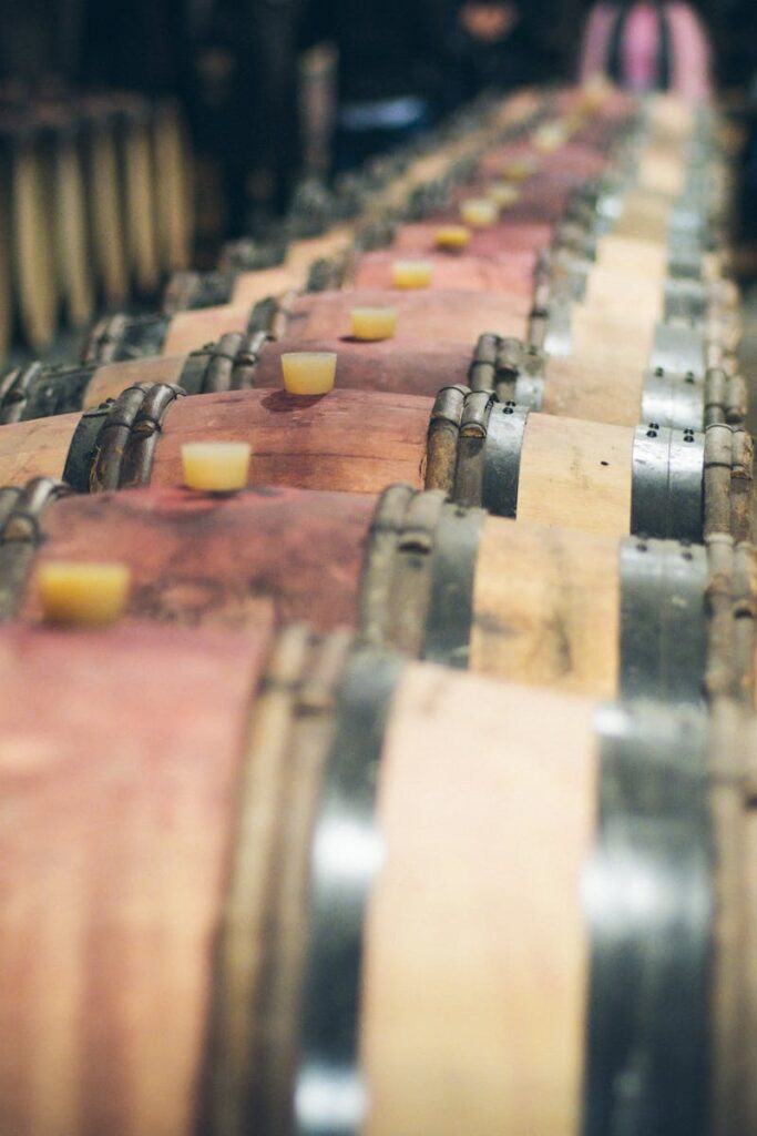 Close-up view of aligned wooden wine barrels aging in a dimly lit cellar.