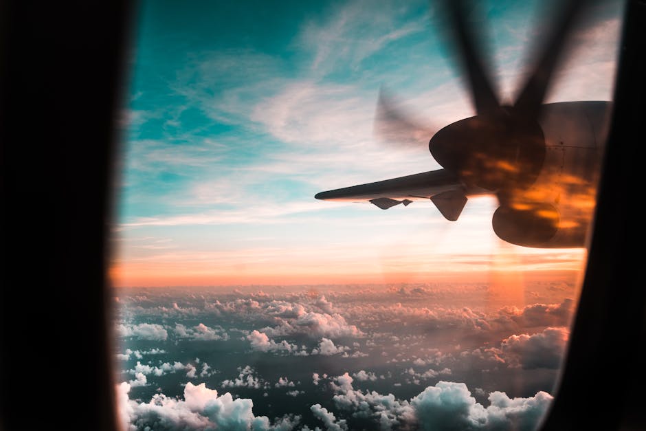 View from a plane window with a propeller against a colorful sunset sky and clouds.