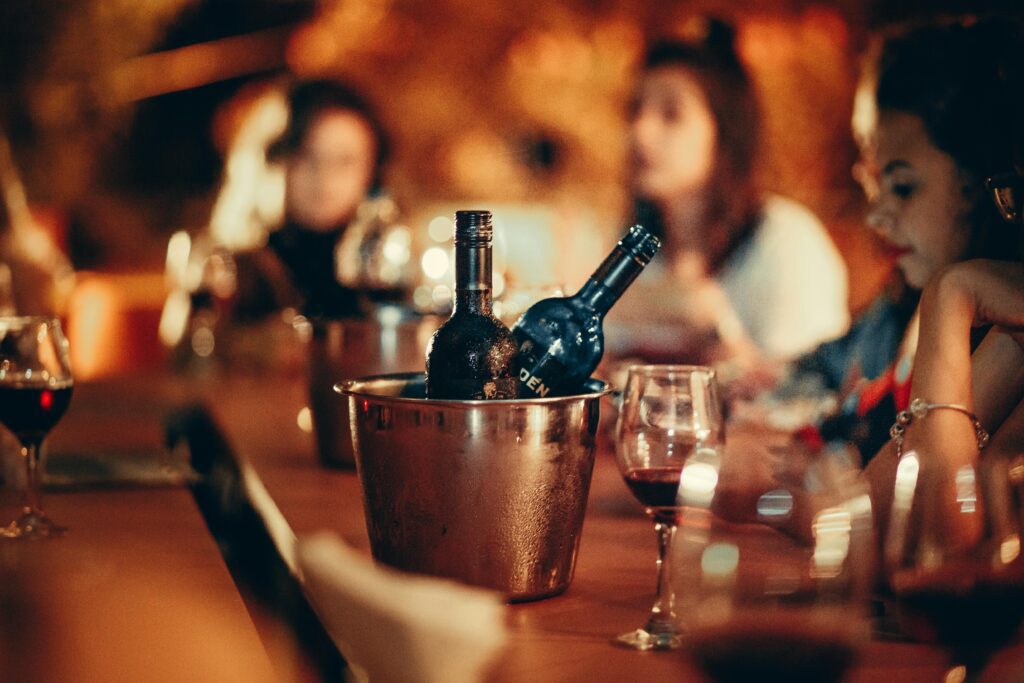 A cozy gathering with wine bottles and glasses on a bar counter, evoking a nightlife atmosphere.